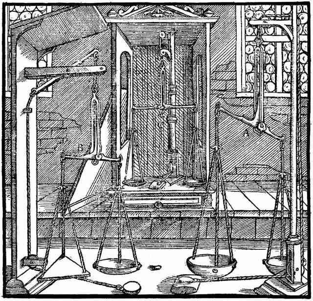 A woodcut: three assay balances hanging in a stone room, their pans empty and level, one of them kept in a glazed case.